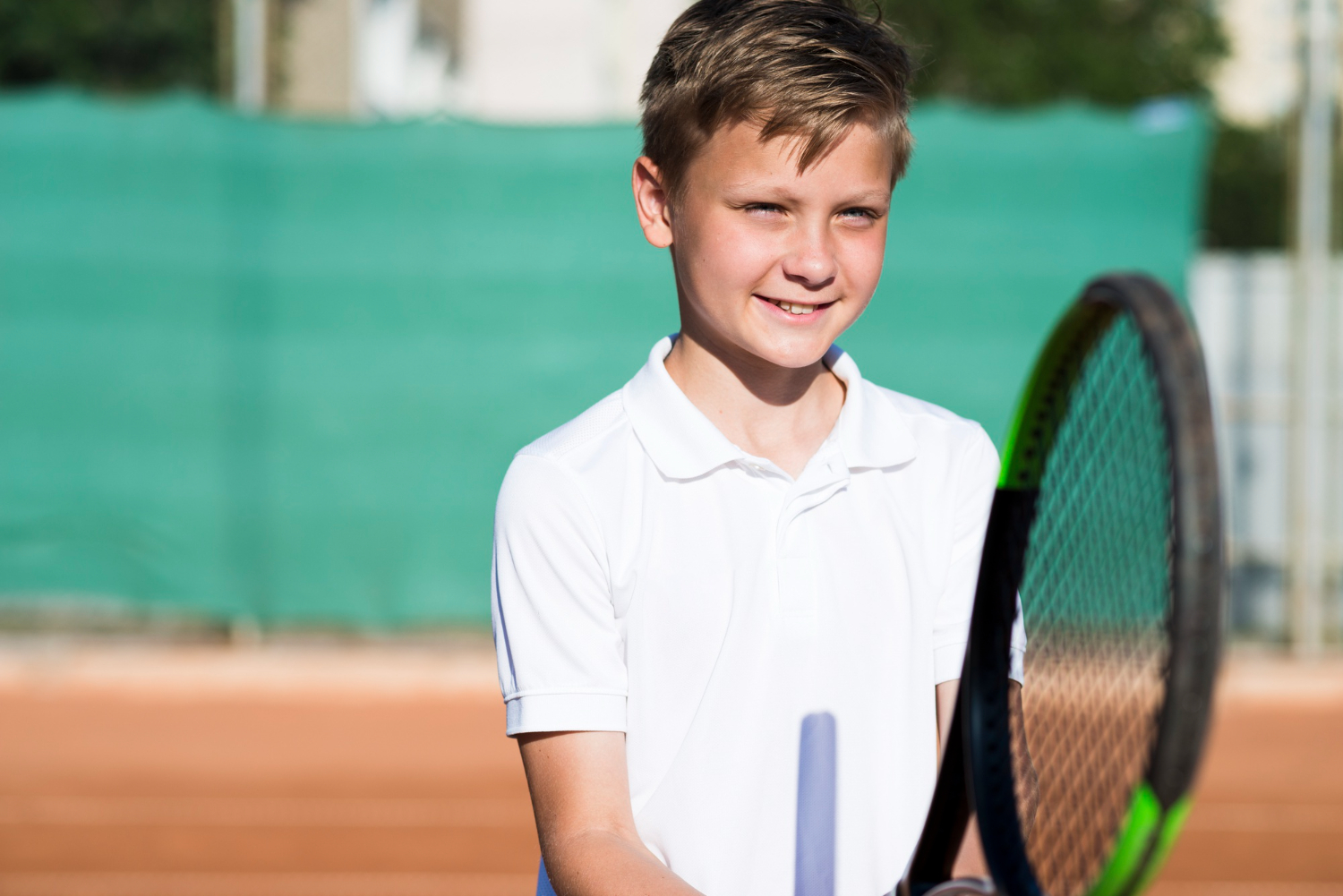 child in white shirt playing tennis