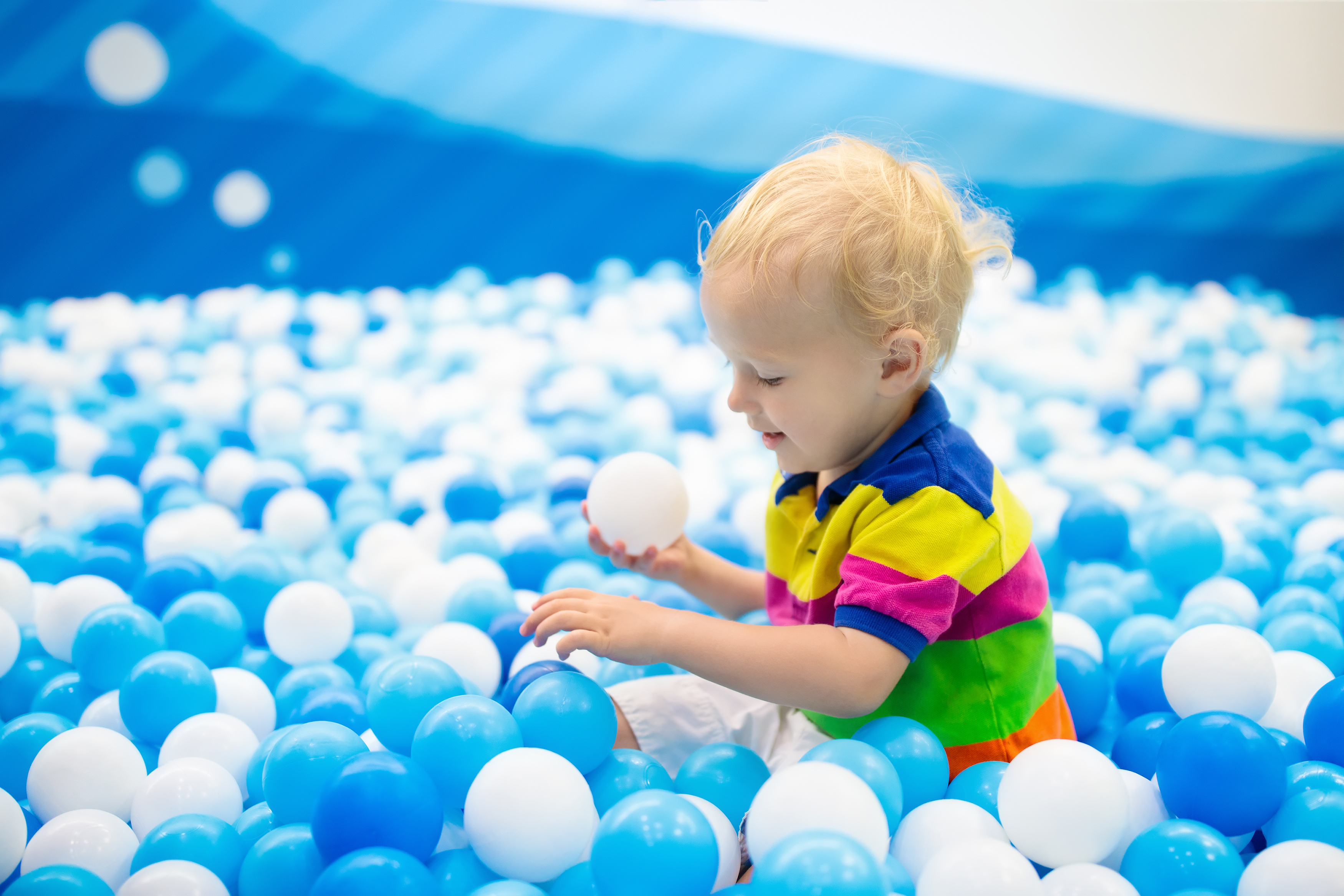 little boy playing in blue ball pit