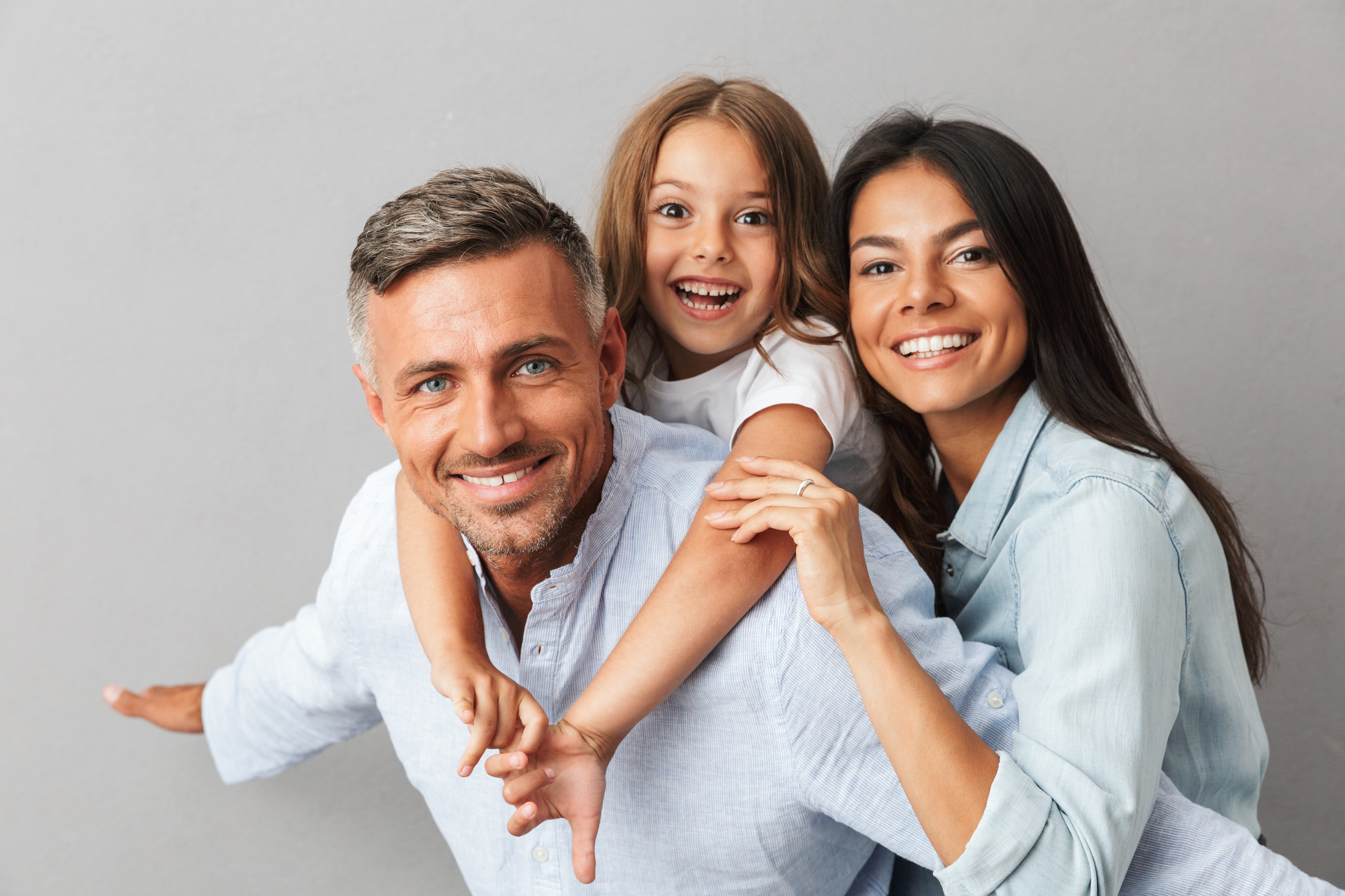 father mother and daughter in group grey background