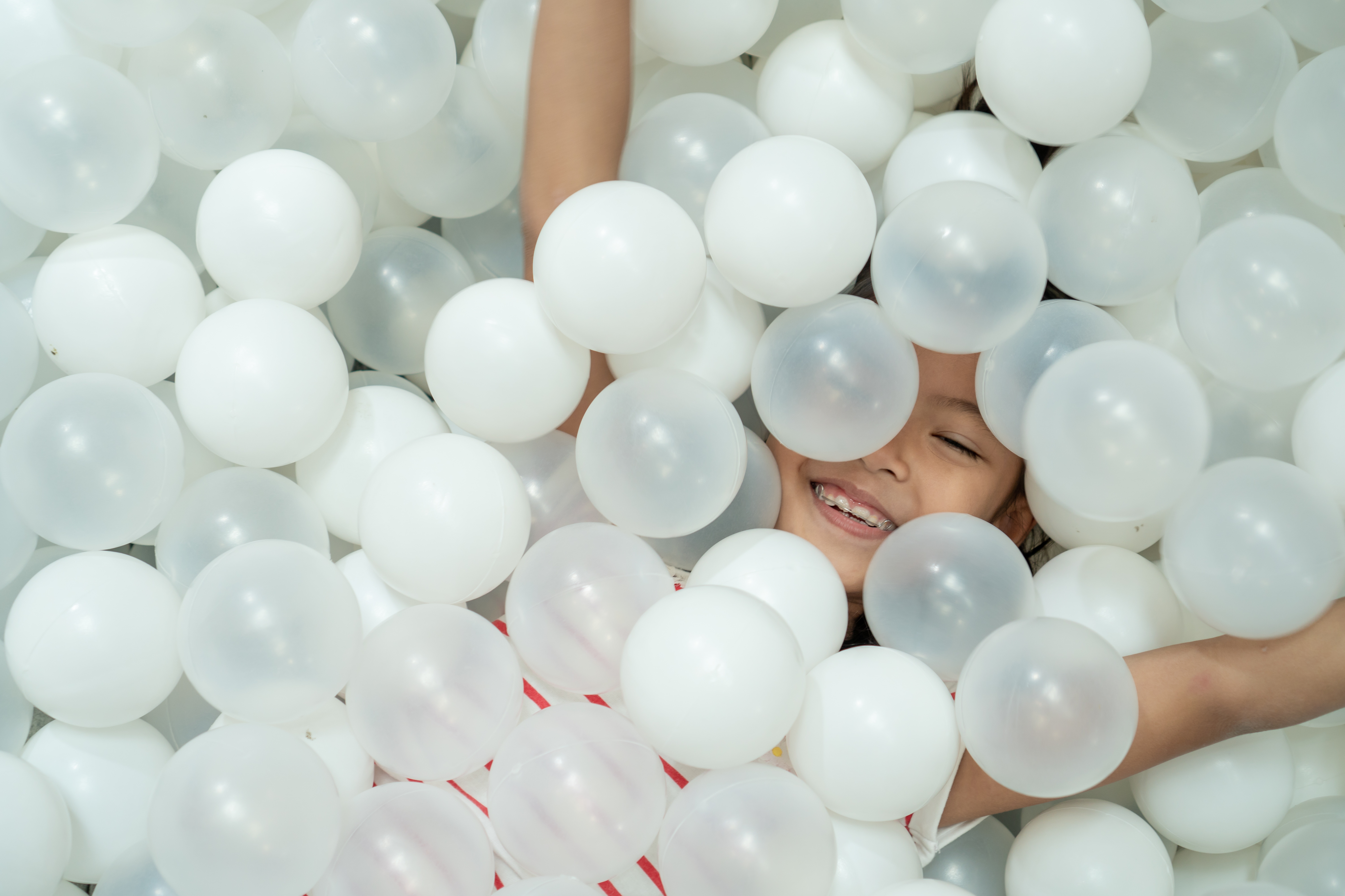 child smiling in white ball pit