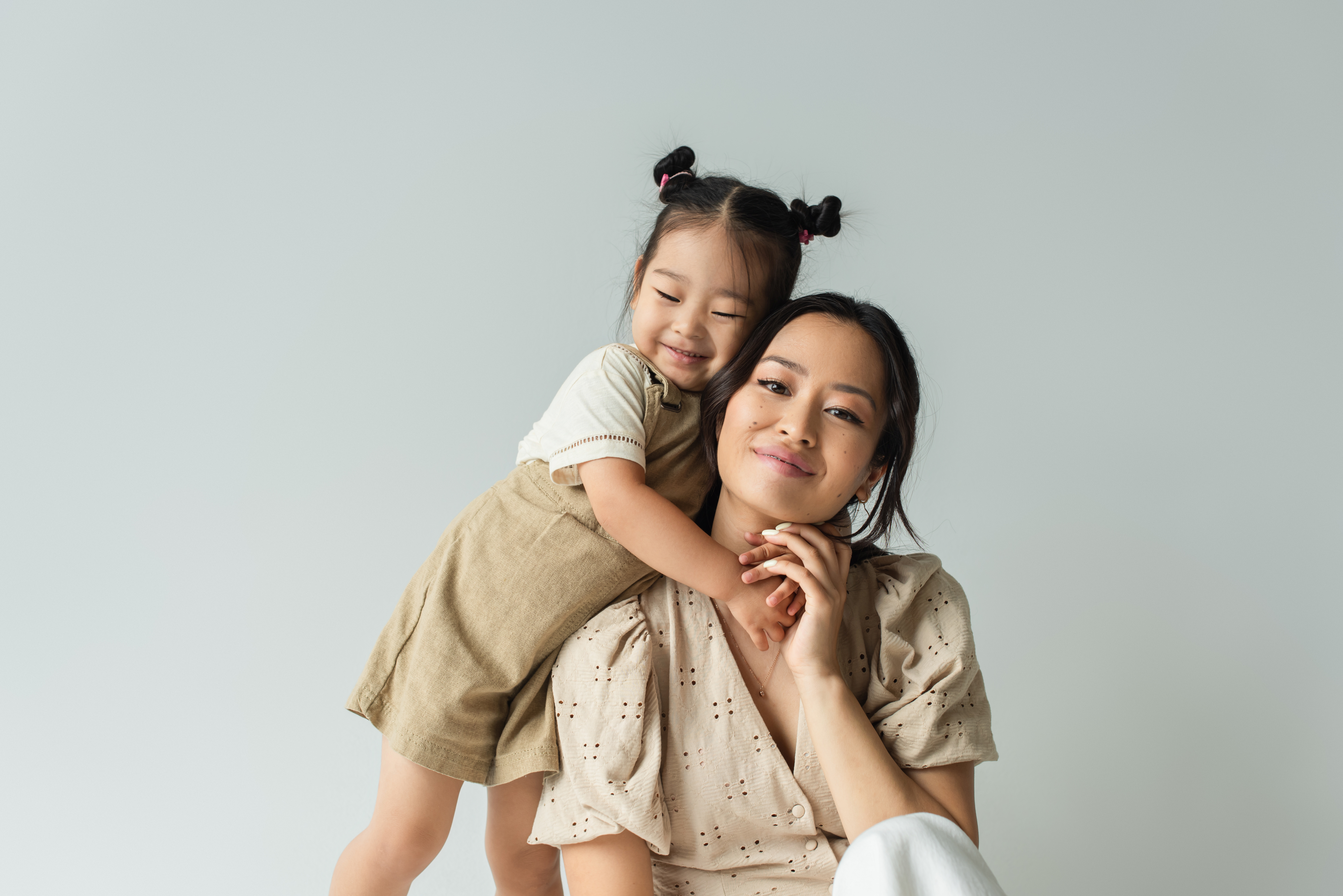 mother and daughter hugging grey background